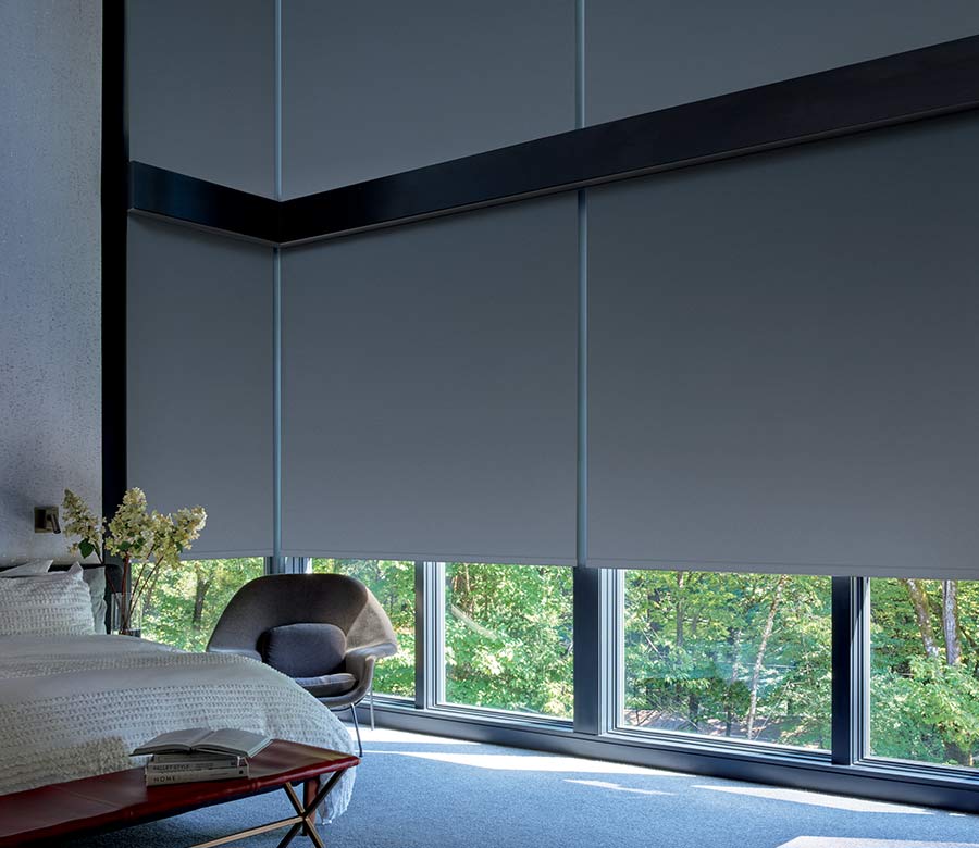 Large corner windows with floor to ceiling roller shades for room darkening