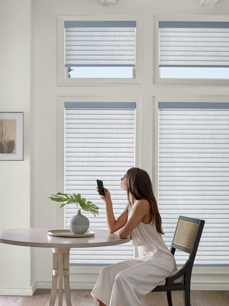 Woman automatically lifting her Sonnette Cellular Roller Shades with a remote