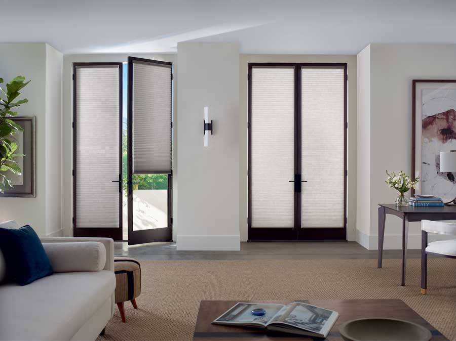 Honeycomb shades covering two identical doors in a neutral living area.