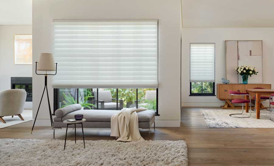 Neutral colored space with a lounge seating area and neutral colored roman shades.