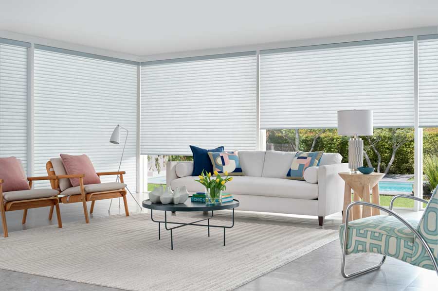 Light colored room with white cellular shades. It features a white couch and chair