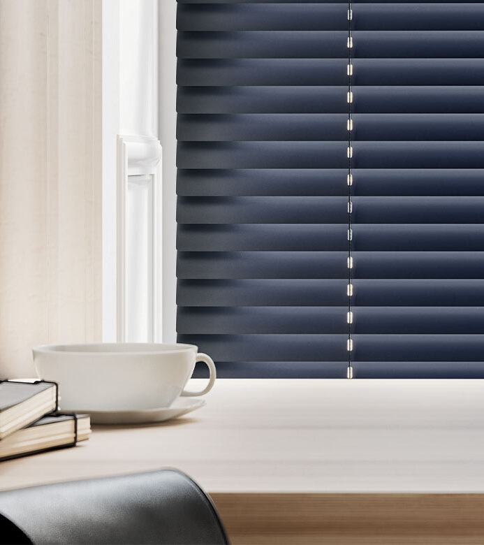 navy blue metal blinds next to coffee cup and notebooks