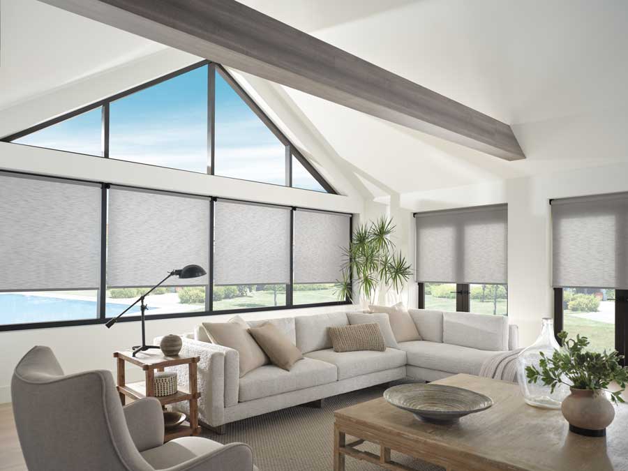 Gray Designer Roller Shades covering large black-trimmed windows and glass doors